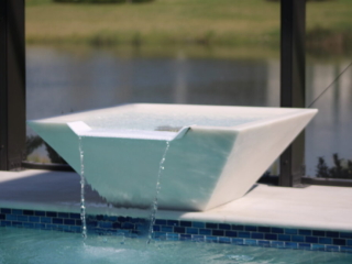 White water bowl spilling into a swimming pool beside blue waterline tile