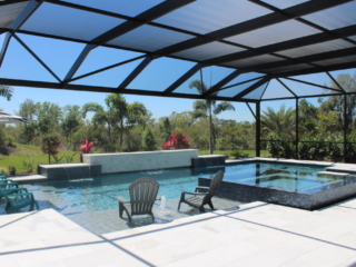 Screened pool and raised spa with a stone water-feature wall and patio seating
