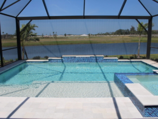 Screened pool and blue-tiled spa overlooking a lake, with arcing water jets