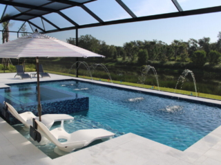 Screened rectangular pool with arcing water jets, raised spa and in-water loungers