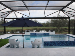 Screened pool and raised spa with white in-water loungers and a shade umbrella