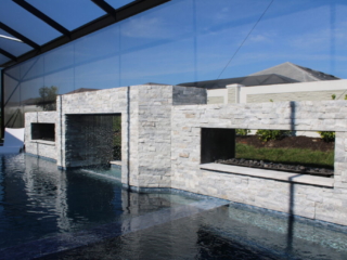 Stone-clad pool wall with a central opening, water features and raised planters