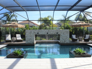 Screened pool with a stone water-feature wall, lounge seating and shade umbrellas
