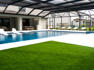 Rectangular screened pool with a white deck and artificial turf beside the covered patio