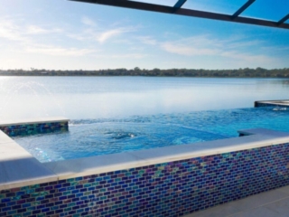 Raised blue-tiled spa beside a screened swimming pool overlooking a lake
